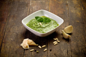 fresh pesto sauce inside a bowl on wooden table